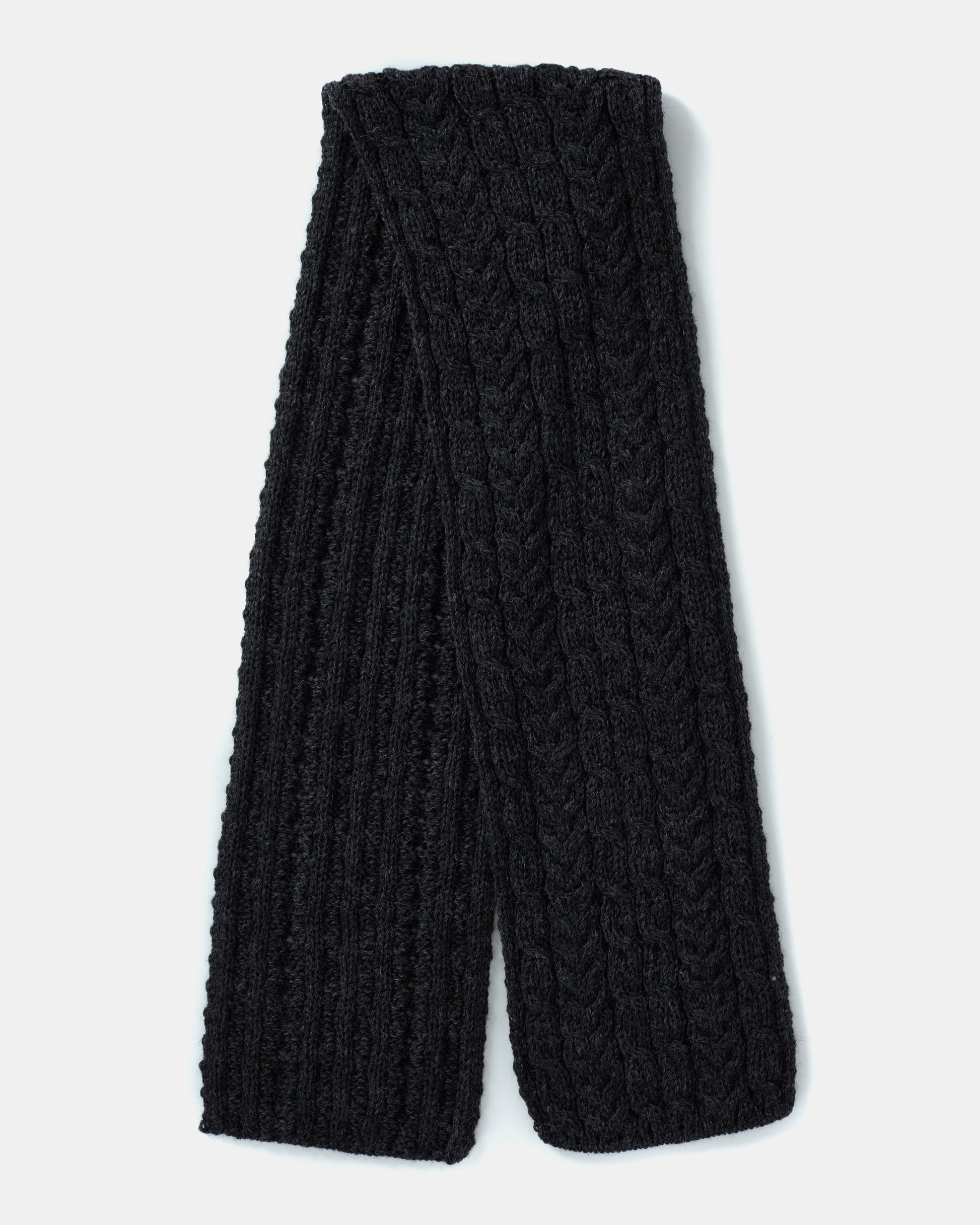 A neatly folded black knitted scarf, crafted from Heritage Worsted Wool and featuring a textured, braided pattern. This Aran Irish Knit Cabel Scarf - B386 by Mjölkshop.se is displayed on a plain white background.