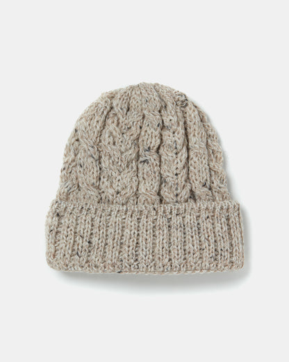 A knitted beige beanie, reminiscent of heritage ull craftsmanship, features a textured cable knit pattern and a folded brim. The hat appears cozy and is likely intended for cold weather wear. The plain white background emphasizes the details of this Aran Irish Knit Cable Hat - B387 by Mjölkshop.se.