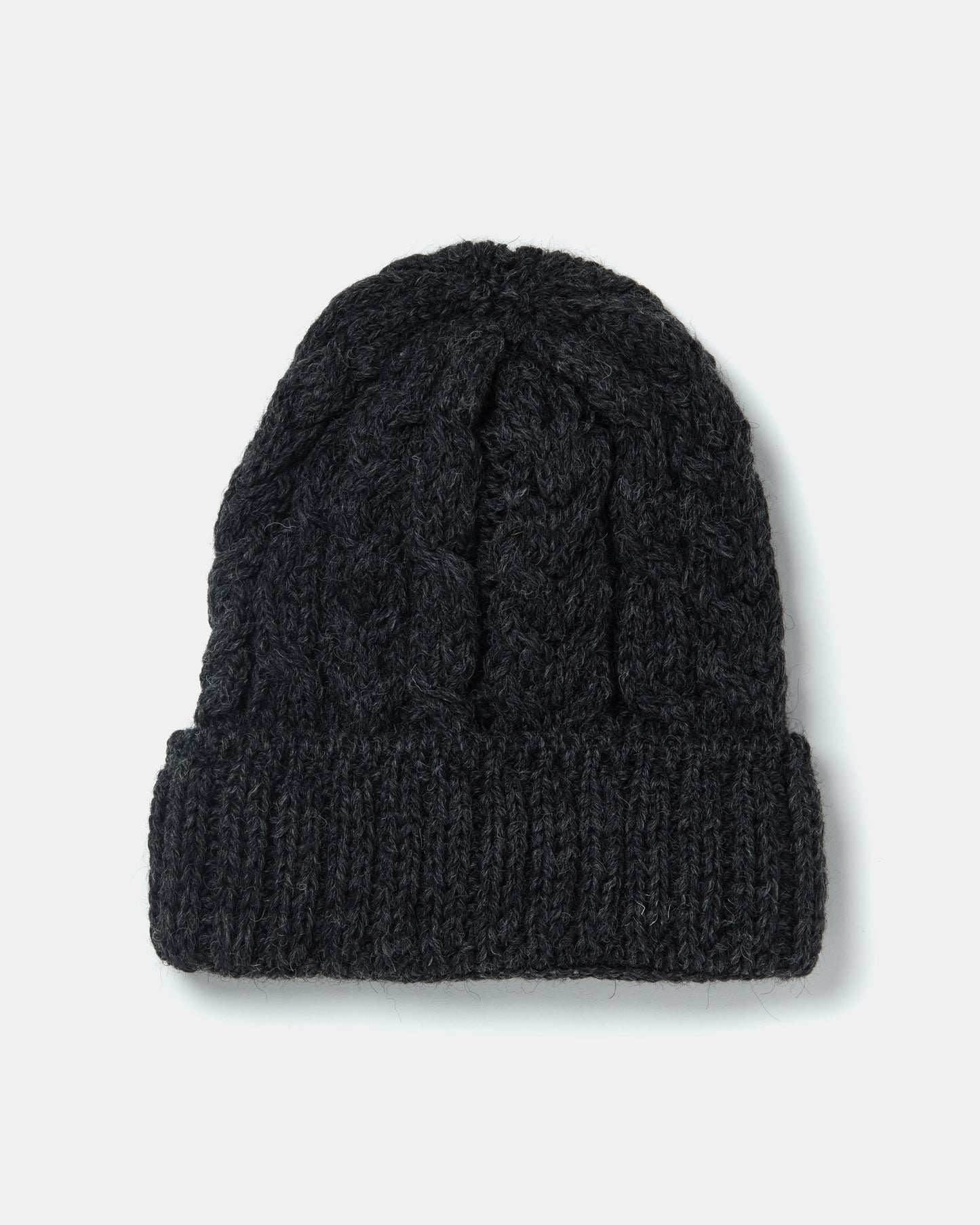 A black, stickad mössa Aran Irish Knit Cable Hat - B387 from Mjölkshop.se with a thick cable-knit pattern and a folded brim is pictured against a plain white background.