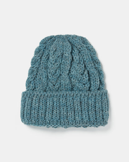 A blue knitted beanie made from Heritage ull, featuring a textured cable knit pattern and a folded ribbed brim, displayed on a white background. The Aran Irish Knit Cable Hat - B387 from Mjölkshop.se.